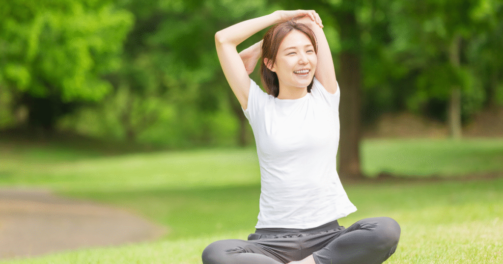 芝生で体操をする若い女性