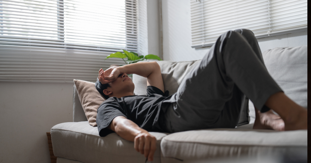 ソファーで寝ころび悩む男性