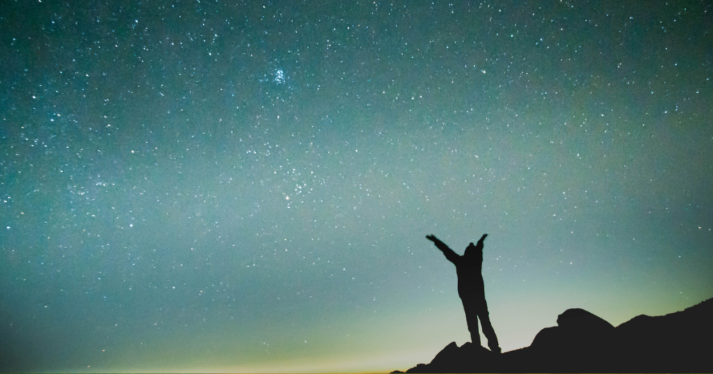 星空に手を広げる人。