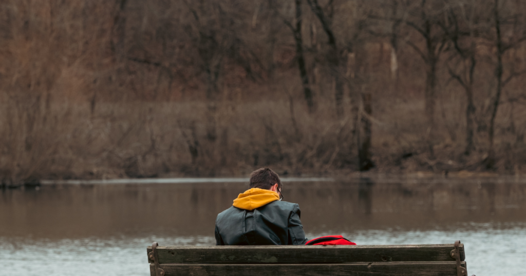 ベンチに座り悩む男性の後ろ姿