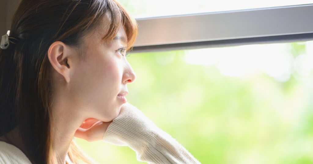 電車の窓から外を眺める女性
